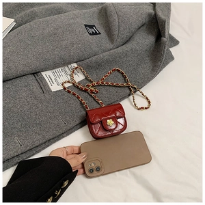 Miniature red quilted crossbody bag with a golden camellia clasp and chain strap