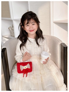 Detail of red knit girls handbag with white bow and elegant pearl handle
