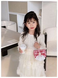Detail of elegant red and white checkered girls' handbag with pearl handle and bow