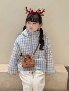 Détail de la tenue d'hiver pour enfant avec veste à carreaux bleus et mini sac en cuir