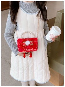 Detailed view of red floral brocade girl's bag with pearl handle and plush bow tassels