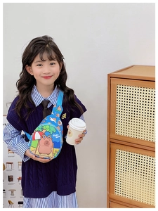 Close-up of a child wearing a blue canvas chest bag with a cute cartoon capybara print