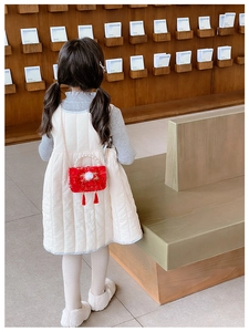 Detail of red girls' crossbody bag featuring festive tassels and pearl handle accessories