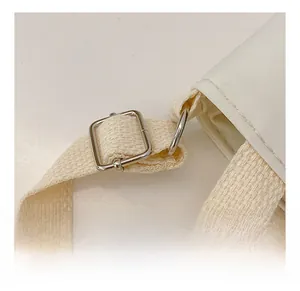 Detail of adjustable canvas strap with silver metal buckle and D-ring on kids shoulder bag