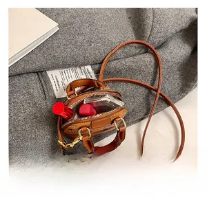 Mini sac à main marron imprimé montrant l'espace intérieur avec rouge à lèvres et poudre