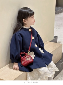 Detailed shot of dark blue wool coat with large wood buttons and red plaid mini bag