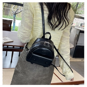 Rückansicht eines Models mit dem kleinen schwarzen PU-Leder-Rucksack in einem Café