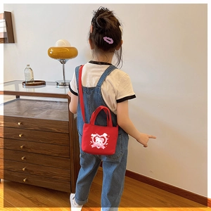Toddler girl wearing a red canvas bear crossbody bag in a cozy home setting
