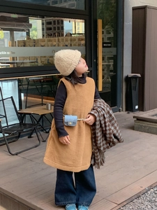 Detail of a blue quilted mini bag on a stylish girl's autumn outfit with yellow vest