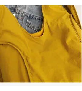 Detail of yellow nylon backpack featuring white fashion print against denim backdrop