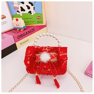 Detail of red velvet girls handbag with pearl handle, bow, and gold chain strap