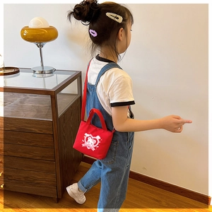 Detailed shot of a red canvas kid's crossbody bag with a cute bear and heart print