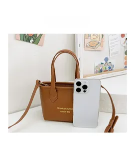 Mini sac seau en cuir marron à côté d'un smartphone pour comparer la taille