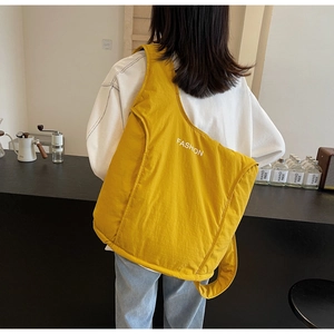 Close-up of bright yellow quilted tote bag with FASHION print on a female model