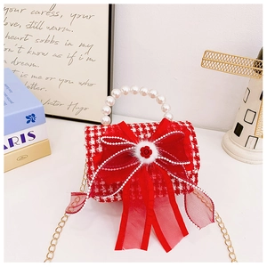 Detail of red tweed girls handbag with pearl handle and large organza bow decoration