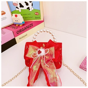Macro shot of red girl's bag with pearl handle and ornate bow on festive background