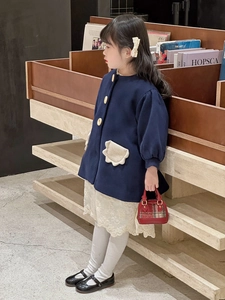 Detail of navy blue wool coat for girls featuring unique cream petal-shaped pockets