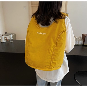 Detail showing bright yellow quilted puffy backpack with Fashion text print