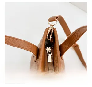 Détail de la fermeture éclair dorée et du cuir marron sur le sac seau pour enfants