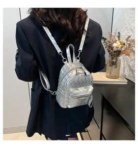 Rear view of model wearing a silver metallic mini backpack with classic woven texture