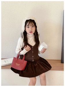 Sac seau enfant en cuir rouge avec tenue en tricot d'automne et jupe plissée en daim