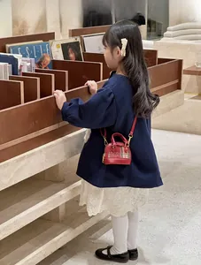 Mini shell-shaped crossbody bag with red leather and vintage plaid worn by a child