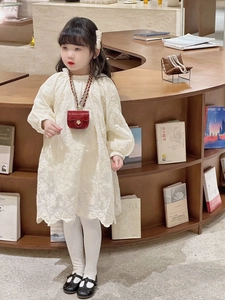 Close-up of white lace dress with floral embroidery and mini red chain shoulder bag