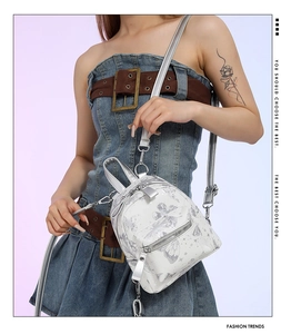 Details des weißen Mini-Rucksacks mit Schmetterlingsprint und silberner Kette
