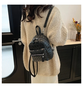 Close-up of the woven texture on a black mini backpack worn by a model in a minimal setting
