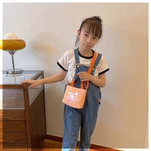 Little girl wearing bright orange canvas bear shoulder bag in a cozy home setting