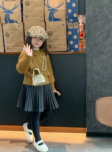 Mini sac blanc à chaîne porté avec un cardigan jaune et une jupe plissée pour fille