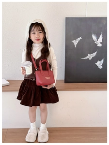 Fillette portant un mini sac seau rouge avec poignées et une bandoulière assortie