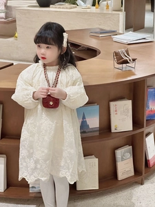 Detail of white floral lace embroidery on kids' dress with red mini chain shoulder bag