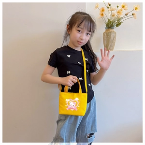 Detail of yellow canvas kids bag featuring cute cartoon bear and heart print with strap