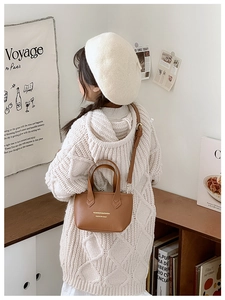Sac seau en cuir marron pour fille porté avec un pull en tricot crème et un béret élégant