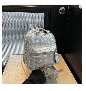 Detail showing metallic silver woven leather texture and zipper of the mini backpack