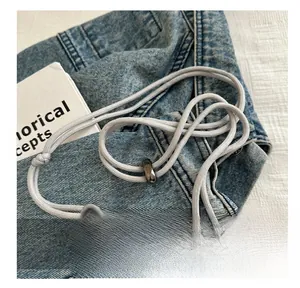 Detail of comfortable braided shoulder strap with adjustable hook on a gray mini bag