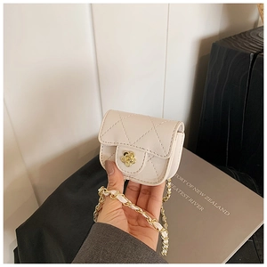 Close-up of a white quilted mini crossbody bag with golden flower clasp and chain strap