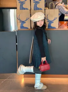 Detailed view of a red mini handbag styled with a child's winter dress and beret outfit