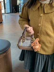 Detail of girls mini plaid handbag with brown leather handles and a cute bear charm