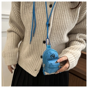 Blue mini backpack-shaped earphone case with lanyard worn by a model in a beige sweater