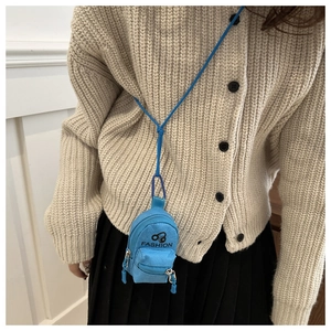 Close-up of sky blue mini backpack coin purse worn with beige knit cardigan
