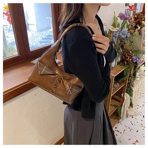 Close-up of brown vintage leather crescent bag with checkered flap and round buckle detail