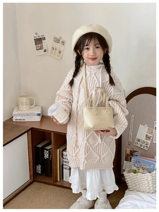 Détail d'une robe en maille beige à capuche pour filles avec motif de torsades