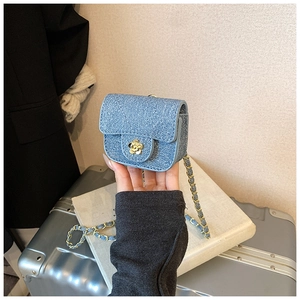 Detail of blue denim quilted mini bag featuring golden flower clasp and chain strap