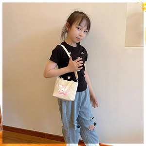 Detail of cute cartoon bear and pink heart print on a cream canvas child shoulder bag