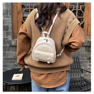 Rückansicht eines Models mit dem cremefarbenen Mini-Rucksack in Retro-Umgebung
