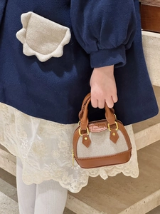 Detailed close-up of girls' mini shell bag with gold zipper and brown leather trim