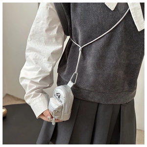 Close-up of silver mini backpack coin purse with fashion logo and long crossbody lanyard