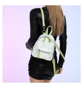 Detail eines Mini-Rucksacks mit grünen Schmetterlingsdrucken auf weißem Mattleder